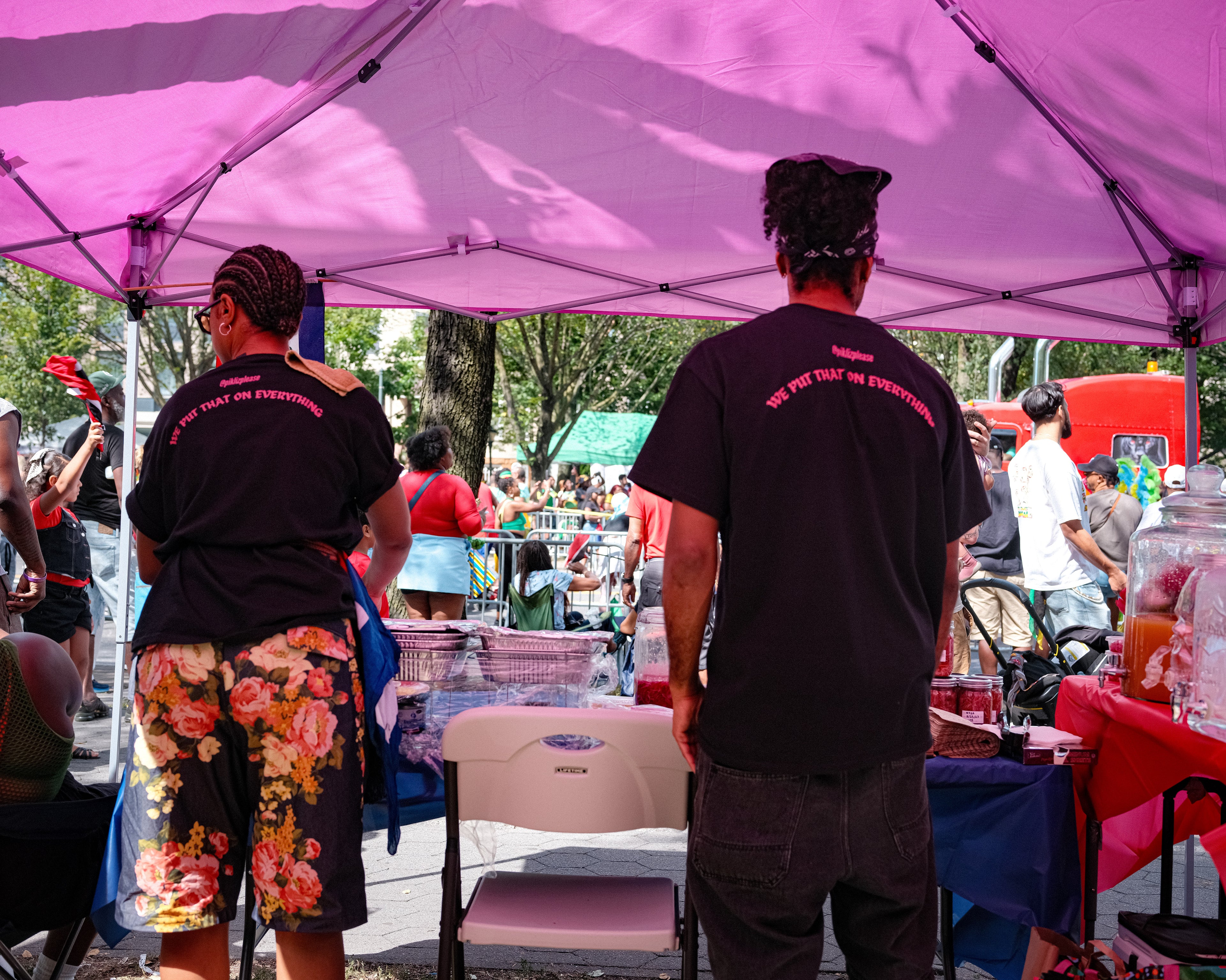 Two people standing under a pink tent at an outdoor event.