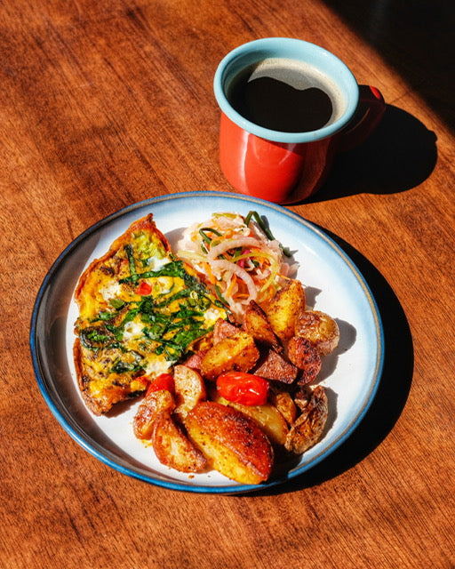 Plate of food with a side of coffee on a wooden table